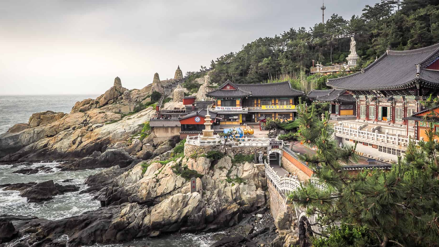 Imagem de Busan com vista para o mar com um templo ao fundo e pedras